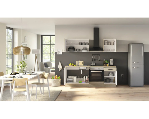 Moderne Wohnküche mit offener Küchenzeile, integriertem Backofen, Dunstabzugshaube und freistehendem Retro Kühlschrank in einem hellen Wohnbereich.