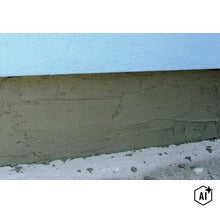 Frisch aufgetragener Sockelputz an einer Hauswand unterhalb der verputzten Fassade. (Image AI modified or generated)