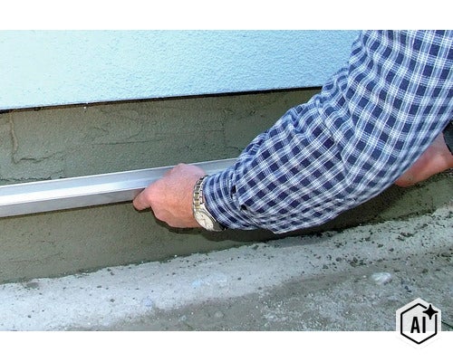 Eine Abziehlatte wird verwendet, um frischen Sockelputz an einer Hauswand glattzustreichen. (Image AI modified or generated)