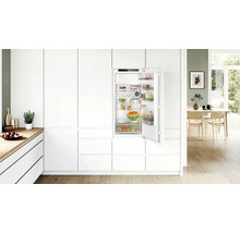 Moderne Einbauküche mit integriertem Kühlschrank in einer hellen und offenen Wohnatmosphäre mit Holzboden.