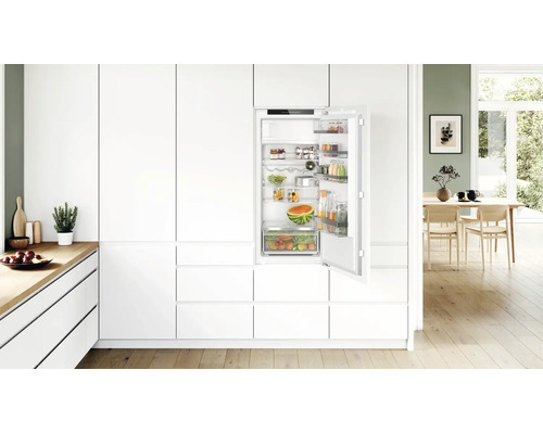 Moderne Einbauküche mit integriertem Kühlschrank in einer hellen und offenen Wohnatmosphäre mit Holzboden.