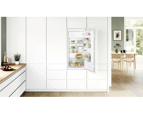 Einbaukühlschrank von Bosch in einer modernen, hellen Küchenzeile mit geöffneter Tür und gefüllten Regalfächern und Obstschublade.