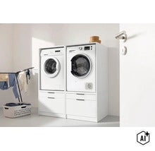 Zwei weiße Waschmaschinenschränke nebeneinander mit Schubladen unten, Waschmaschine und Trockner erhöht aufgestellt in einer Waschküche. (Image AI modified or generated)