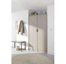 Modernes Entree mit beigem zweitürigen Garderobenschrank, Holzbank, Kleiderhaken an weißer Wand und rundem Teppich.