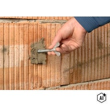 Hand setzt einen Anker in eine mit Mörtel gefüllte Bohrung in einer Ziegelwand ein. (Image AI modified or generated)