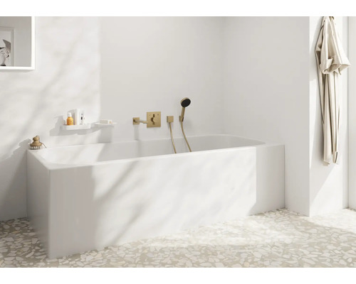 Modernes Badezimmer mit weißer Einbauwanne und Unterputz Armatur in Metalloptik an der Wand, sowie Terrazzoboden und Bademantel am Haken.
