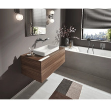 Modernes Badezimmer mit Waschtisch in Holzoptik, weißem Aufsatzwaschbecken, integrierter Badewanne, Wandarmaturen und stimmungsvoller Beleuchtung.