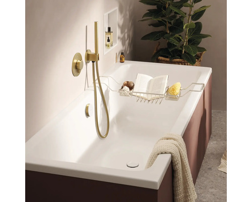 Moderne Badewanne mit goldfarbener Unterputzarmatur und Handbrause sowie einer Ablage aus Metall mit Buch und Schwamm in einem Badezimmer.