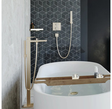 Modernes Badezimmer mit freistehender Badewanne, bodenstehender Wannenarmatur und Unterputz Armatur mit Handbrause vor geometrischen Wandfliesen.