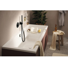Moderne Badewanne mit Wannenablage, Buch, Schwamm und Duscharmatur. Ein stilvolles Badezimmerambiente mit Handtuch und Ablagehocker.