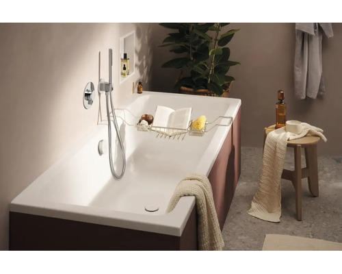 Moderne Badewanne mit Wannenablage aus Metall in einem elegant eingerichteten Badezimmer mit Duscharmatur und Holzschemel als Ablagefläche