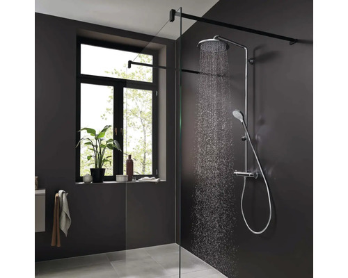 Moderne begehbare Dusche mit Duschsystem und Glaswand in einem Badezimmer mit dunklen Wänden und einem Fenster.