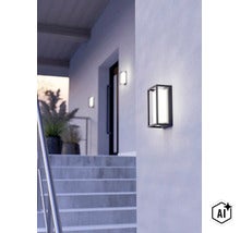 Moderne rechteckige Außenwandleuchte montiert an einer hellen Fassade neben einer Hauseingangstreppe. (Image AI modified or generated)
