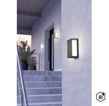 Moderne rechteckige LED Außenwandleuchte mit Rippendesign montiert an einer Hausfassade neben einer Treppe. (Image AI modified or generated)