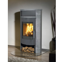 Moderner Kaminofen mit Specksteinverkleidung und brennendem Feuer hinter einer Glasscheibe sowie integriertem Holzfach.