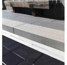 Moderne Terrassen Gestaltung mit dunklen Bodenplatten und einer massiven Sitzbank aus Holz an einer Betonmauer mit integrierter Entwässerungsrinne