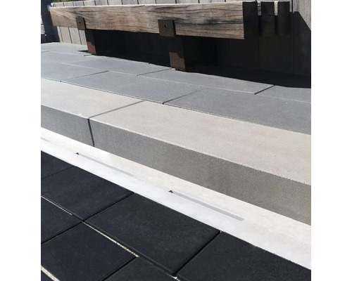 Moderne Terrassen Gestaltung mit dunklen Bodenplatten und einer massiven Sitzbank aus Holz an einer Betonmauer mit integrierter Entwässerungsrinne