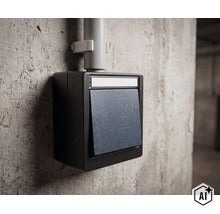 Aufputz Lichtschalter in einem robusten Gehäuse montiert an einer Betonwand mit Kabelführung. (Image AI modified or generated)