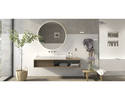 Modernes Badezimmer mit rundem LED Spiegel und wandhängendem Waschtisch mit Holzkonsole vor einer Wand mit hellen Fliesen.
