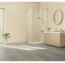 Modernes Badezimmer mit ebenerdiger Duschkabine aus Glas, Waschtisch mit Holzunterschrank und ovalem Spiegel vor hellen Wandfliesen.