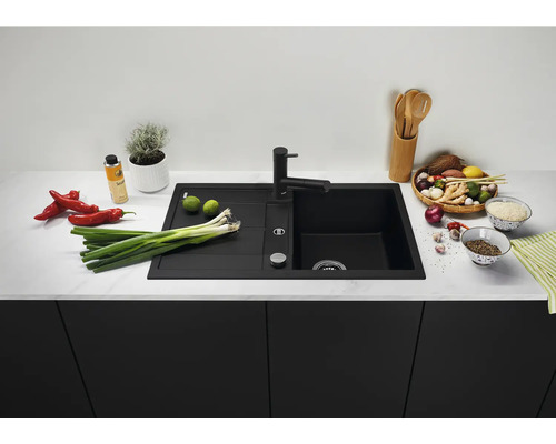 Moderne schwarze Einbauspüle mit Abtropffläche und passender Küchenarmatur in einer stilvollen Küche mit Lebensmitteln auf der Arbeitsplatte
