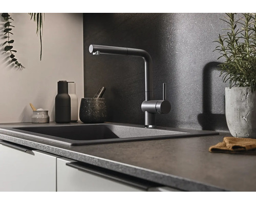 Moderne Küchenarmatur mit Ausziehbrause an einem dunklen Spülbecken in einer stilvollen Küche mit dunkler Rückwand.
