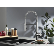 Moderne Küchenarmatur mit Spiralfeder und ausziehbarer Schlauchbrause montiert an einer Spüle mit Arbeitsplatte in einer Küche.