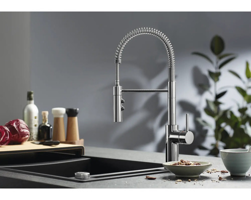 Moderne Küchenarmatur mit Spiralfeder und ausziehbarer Schlauchbrause montiert an einer Spüle mit Arbeitsplatte in einer Küche.