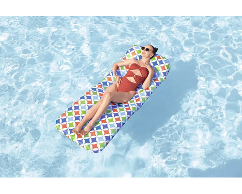 Eine Person entspannt auf einer bunten Luftmatratze mit geometrischem Muster auf der Wasseroberfläche eines Swimmingpools.