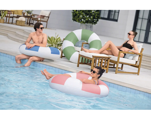 Drei Personen entspannen sich an einem Pool mit verschiedenen gestreiften Schwimmringen aus Kunststoff.