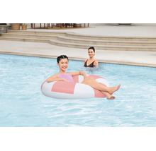 Ein junges Mädchen entspannt in einem runden aufblasbaren Schwimmreifen in einem Swimmingpool, im Hintergrund ist eine weitere Person zu sehen.