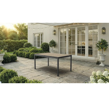 Gartentisch mit Holzoberfläche und Metallgestell auf einer gepflasterten Terrasse vor einem Wohnhaus mit großen Fenstertüren.