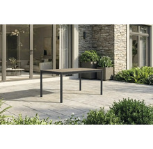 Moderner rechteckiger Gartentisch mit Metallgestell und Tischplatte in Holzoptik auf einer Steinterrasse vor einem Haus.