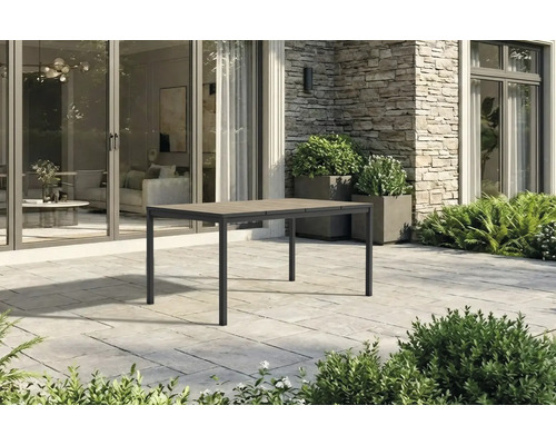 Moderner rechteckiger Gartentisch mit Metallgestell und Tischplatte in Holzoptik auf einer Steinterrasse vor einem Haus.