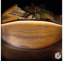 Moderne Bar mit Theke aus Stampflehm mit indirekter Beleuchtung im Innenbereich. (Image AI modified or generated)
