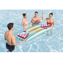 Vier Personen spielen Bierpong auf einer aufblasbaren Schwimminsel mit integrierten Becherhaltern in einem Swimmingpool.