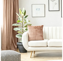 Strukturkissen auf einem modernen weißen Sofa im hellen Wohnzimmer mit Zimmerpflanze und Vorhängen