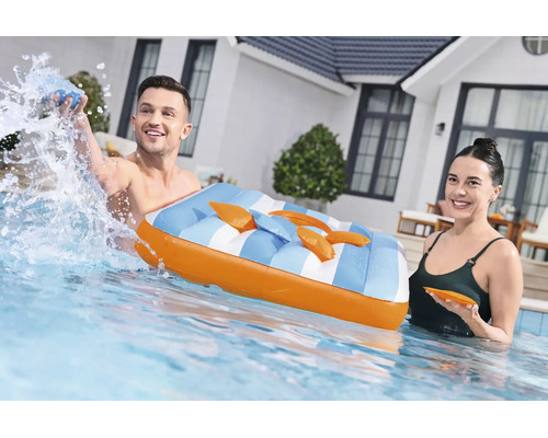 Ein Paar mit einer aufblasbaren Luftmatratze im Gartenpool vor einem modernen Haus.