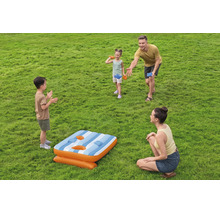 Familie spielt mit einem aufblasbaren Bean Bag Wurfspiel im Garten auf einer Rasenfläche.