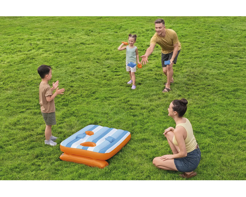 Familie spielt mit einem aufblasbaren Bean Bag Wurfspiel im Garten auf einer Rasenfläche.
