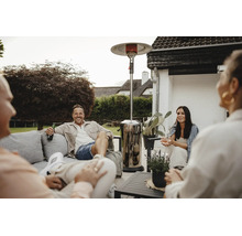 Gruppe von Freunden sitzt abends auf einer Terrasse mit einem Terrassenheizstrahler für behagliche Wärme.