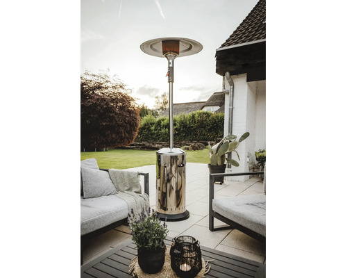 Ein Terrassenstrahler aus Edelstahl auf einer Steinterrasse mit Loungemöbeln in einem Garten.