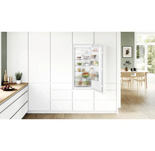 Einbaukühlschrank von Bosch in einer modernen, hellen Küche mit weißen Küchenfronten und offenen Regalen im Innenraum.
