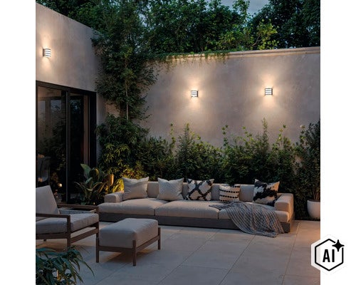 Moderne Außenwandleuchten montiert an einer Gartenmauer über einem gemütlichen Lounge Bereich mit Sofa und Sessel am Abend. (Image AI modified or generated)