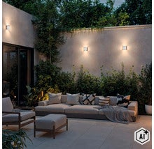 Moderne Außenwandleuchten montiert an einer Gartenmauer über einem gemütlichen Lounge Bereich mit Sofa und Sessel am Abend. (Image AI modified or generated)