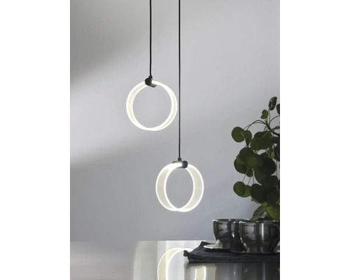 Moderne LED Pendelleuchte mit zwei runden Lichtringen in hängender Anordnung über einem Tisch mit Dekoration.