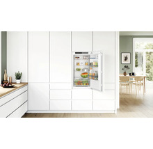 Einbaukühlschrank von Bosch in eine moderne weiße Küchenzeile integriert mit offener Tür und gefüllten Ablagefächern.