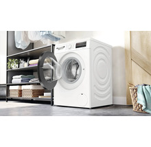 Bosch Waschmaschine mit offener Tür in einer Waschküche mit Regalen und Wäschekorb.