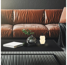 Wohnzimmer mit Ledersofa, Couchtisch, dekorativer Vase mit Pflanze und moderner, leuchtender Tischleuchte.