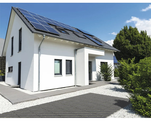 Modernes Einfamilienhaus mit Solaranlage auf dem Dach und einer gepflegten Außenanlage mit gepflastertem Weg und Kiesbett.